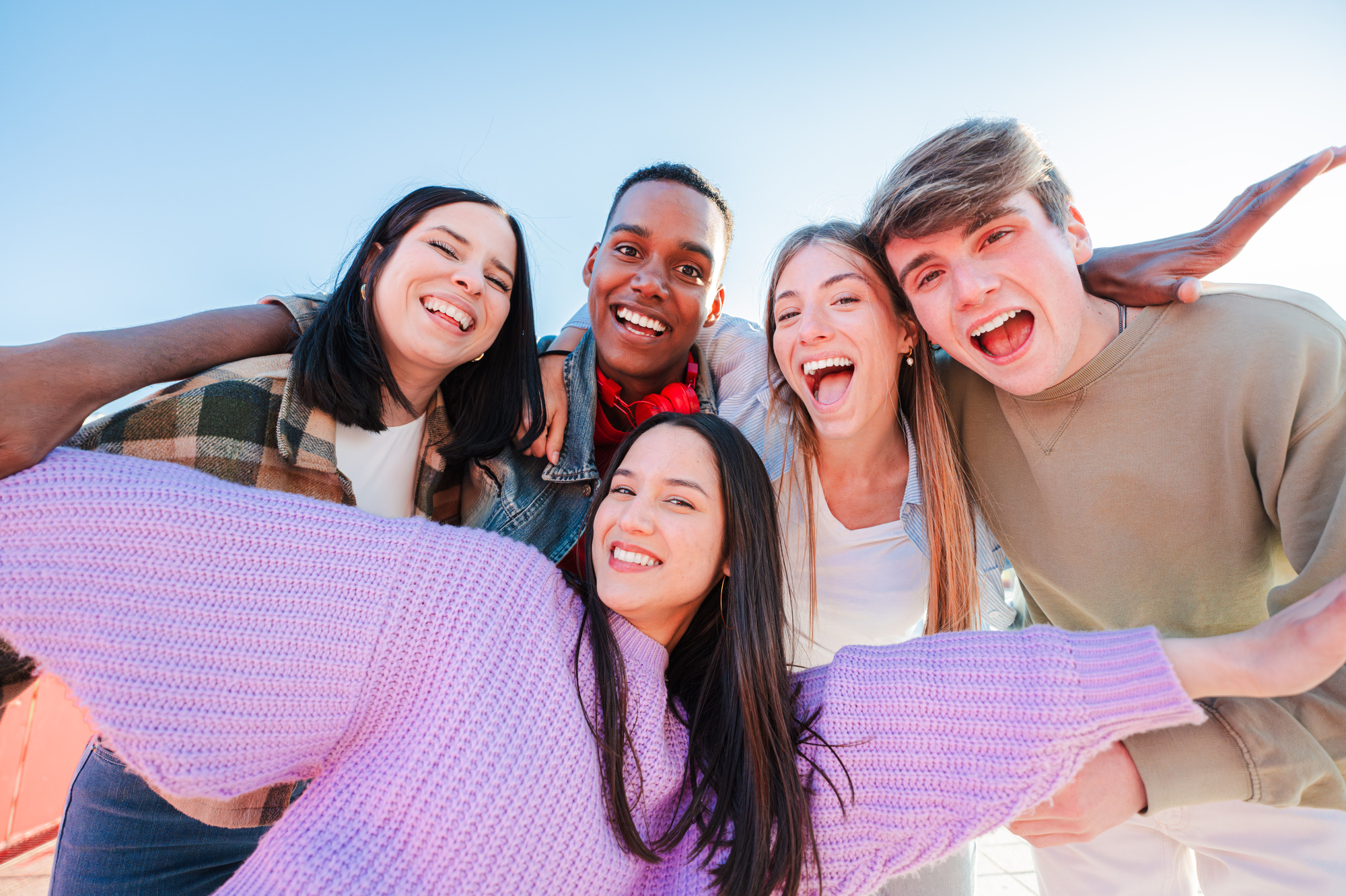 group of real multiracial teenagers having fun together and posing for a portrait. young friends smiling and laughing. multiethnic people bonding outside with positive and friendly expression